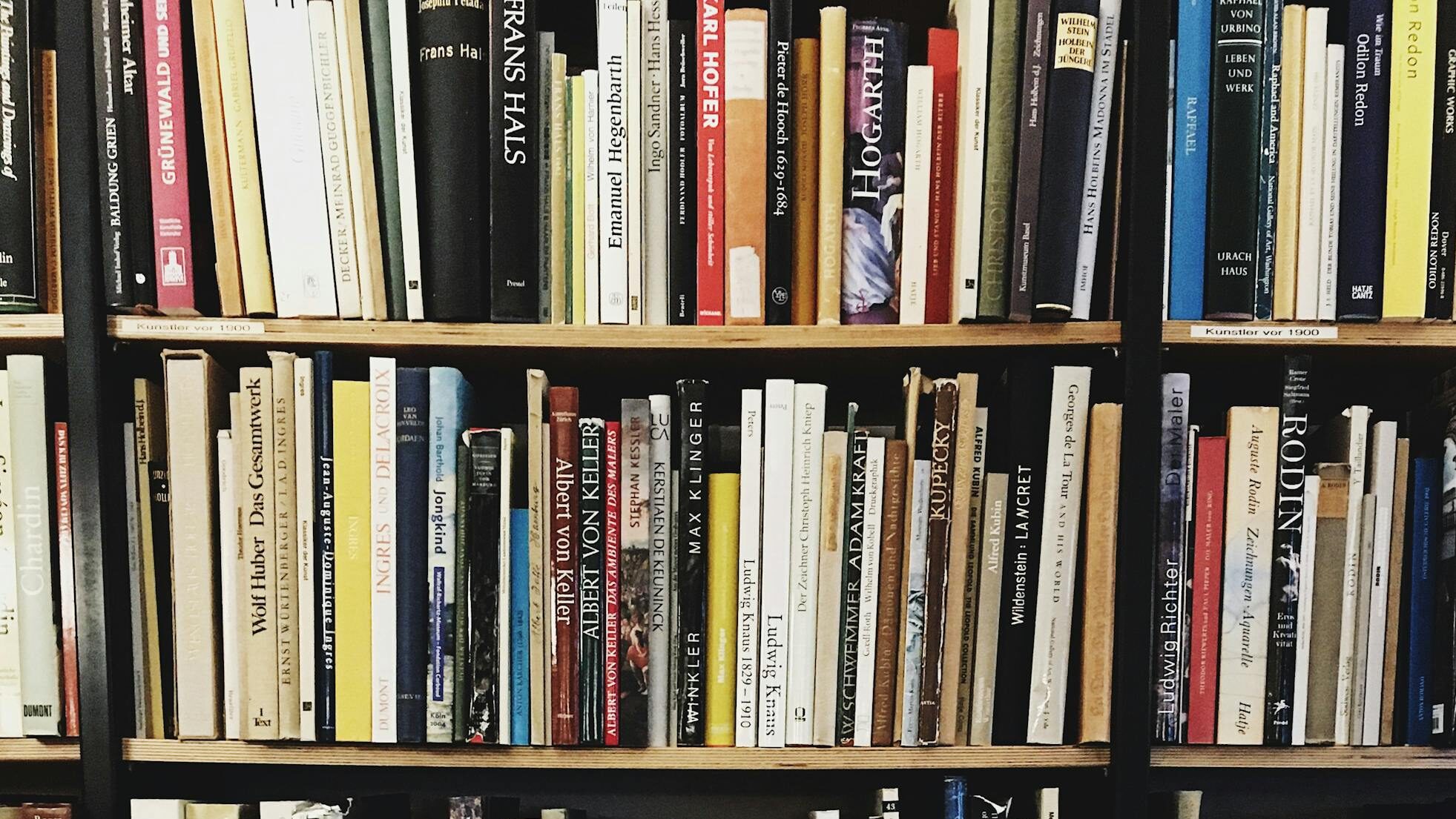 A vibrant bookshelf filled with diverse hardcover books in a cozy library setting.